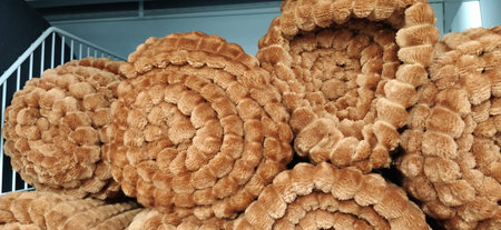 Soft fluffy beige rugs folded into skeins, rolls and bundles. Assortment of brown bedspreads on a...
