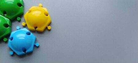 Multi-colored details from the childrens designer on a gray background. Yellow, green, blue plastic discs for the development of fine motor skills of fingers.の写真素材