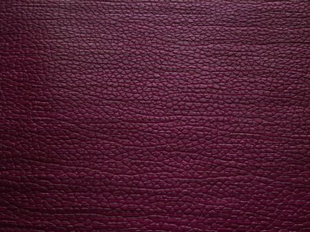 Faux leather burgundy. Separate grooves and elevations on the surface of a bag or shoe. Reflection of the light. Fashion accessory made of faux pig skin. Close-up.の写真素材