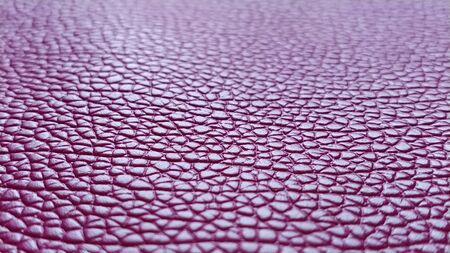 Artificial leather is bright pink or fuchsia. Distinct furrows and elevations on the surface of a bag or shoe. Reflection of the light. Fashion accessory made of imitation pig skin. Close-up.の写真素材