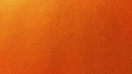 A sheet of thick paper of bright orange color. Close-up. Background intense shade. Natural lateral lighting. Fine cardboard or paper texture. Light gradient in degree of illumination.の写真素材
