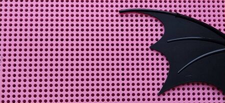 Black bat wing made of plastic. Pink panel with holes for mosaic. Details of childrens toys.の写真素材