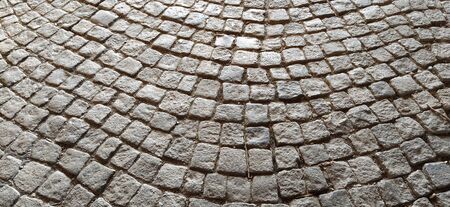 Ancient pavement. Sidewalk made of gray stones. Cobblestones on the square of the old city. Uneven tiles laid in a circle. Natural stone texture.の写真素材