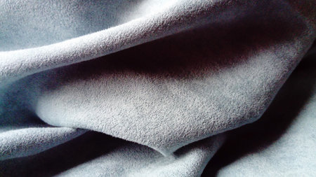 close-up of velvety thick fabric for curtains of gray-blue color pleated with the play of...