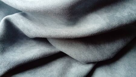 close-up of velvety thick fabric for curtains of gray-blue color pleated with the play of chiaroscuro.の写真素材