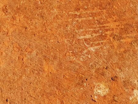Brick or stone close-up. Texture or background. Bright red, brown, orange, beige colors. Dust, small pebbles, sand, soil and moss on uneven surfaces.Environmental impact. Natural daylight or sunshine.の写真素材