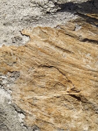 Brick or stone close-up. Texture or background. Bright red, brown, orange, beige colors. Dust, small pebbles, sand, soil and moss on uneven surfaces.Environmental impact. Natural daylight or sunshine.の写真素材
