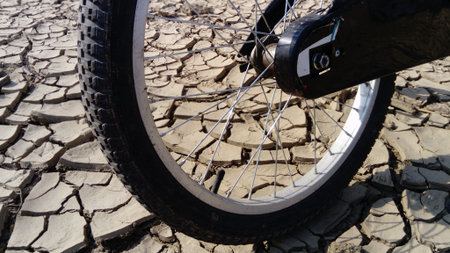 The front wheel of a school bike against a background of dried up cracked clay soil. Racing in the...
