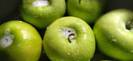 Wet soapy green apples. Thoroughly wash vegetables and fruits with water and soap. Prevention of infectious diseases. Apples close up. Vegetarianism. High glycemic index. Soapy foam sparkles in sunlight.の写真素材