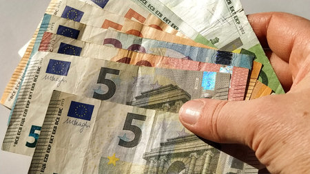 Euro paper notes. European currency on a white background close-up. Hand and fingers of an elderly...