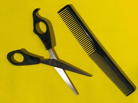Hairdressing scissors and comb on a bright yellow background. Hairdresser tools. Hairdressing salon equipmentの写真素材