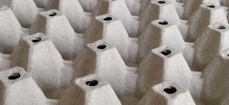 cardboard container for eggs close-up. Smooth rows, forms for laying eggs. Abstraction with convex and indented elements. Light and shadow. Rounded holes. Banner.の写真素材