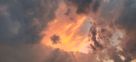 Dramatic beautiful storm clouds during sunset. Cumulus clouds illuminated in orange and pink. Dark...