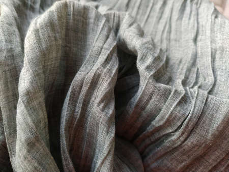 curtains or tulle in the Scandinavian style. Gray pleated fabric or wrinkled textile hangs down. Close-up. The bottom edge of the curtain lies on a horizontal surface. Soft focus.の写真素材
