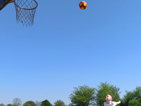 The boy throws the ball into the basketball net. The child plays with a ball on the playground. Free...
