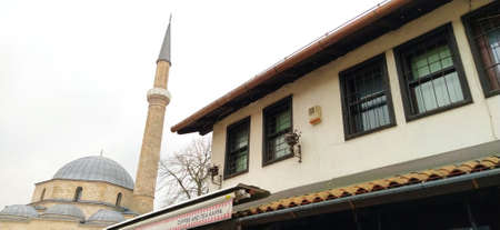 Sarajevo, Bosnia and Herzegovina, 8 March 2020, an old Turkish style commercial building with the main mosque and minaret in the background. Gazi Husrev-begova dzamija. Tower of a mosque.のeditorial素材