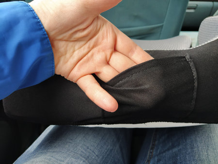A woman's hand thrust into the pocket of a child car seat and demonstrating the quality of the...
