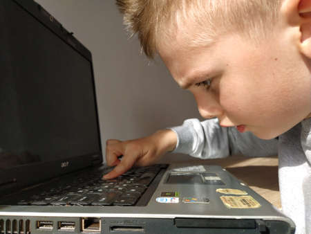 Sremska Mitrovica, Serbia, May 20, 2020 Blond boy with laptop. The child looks at the monitor. Pensiveness on the face.のeditorial素材