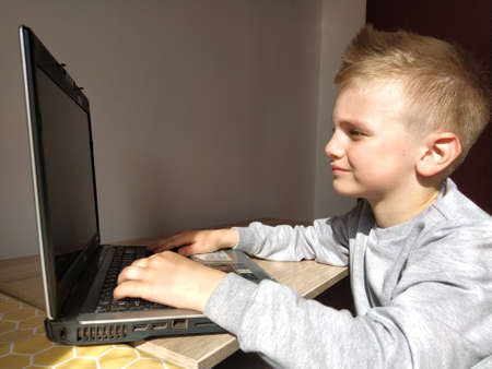 Sremska Mitrovica, Serbia, May 20, 2020 Blond boy with laptop. The child looks at the monitor. Pensiveness on the face.のeditorial素材