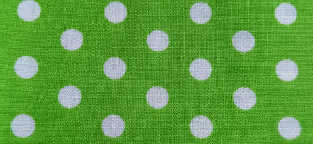 Green fabric with polka dots. White circles. Close-up. Fabric for sewing dresses and home furnishings. Banner.の写真素材