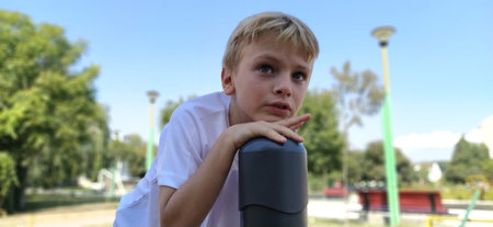 Pensive boy on the playground. The child lingered on top of the metal structure, and thought. Boy...