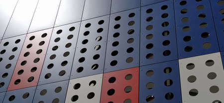 Facade of a modern building. Red, blue and white slabs or metal profiles with decorative holes. Technological solutions in the exterior. Building supporting structures under decorative elements.の写真素材
