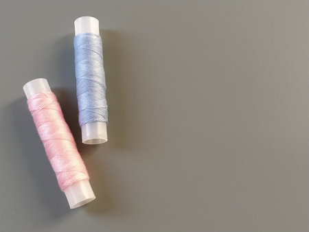 Spools of pink and blue thread on a gray background. Textile industry.