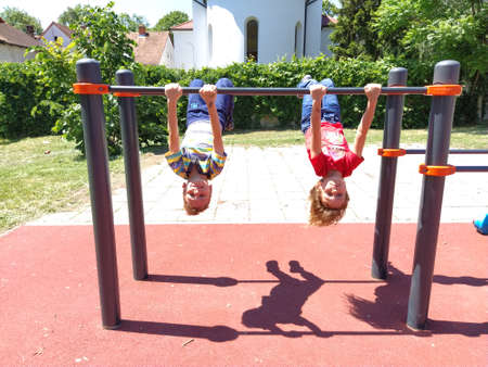 Sremska Mitrovica, Serbia. June 6, 2020. Flip-flops, weight lifting and weights, strength exercises. Two teenagers go in for sports on simulators, children on a sports ground.のeditorial素材