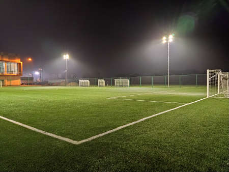 stadium in lights and flashes. Empty beautiful football field with glowing spotlights in the evening or at night. Artificial turf. Fog or smoke effect. Football goal.のeditorial素材