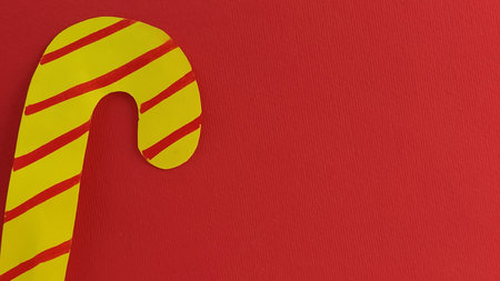Lollipop on a red background. Imitation of yellow candy with red stripes. New Year or Christmas...