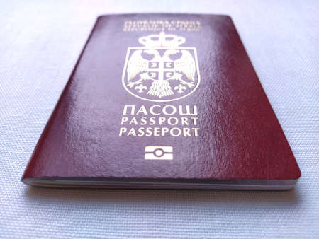 Serbian passport. New biometric document for border crossing. Official documentation. Red and burgundy passport crusts with shiny letters. The surface of the passport reflects light.のeditorial素材