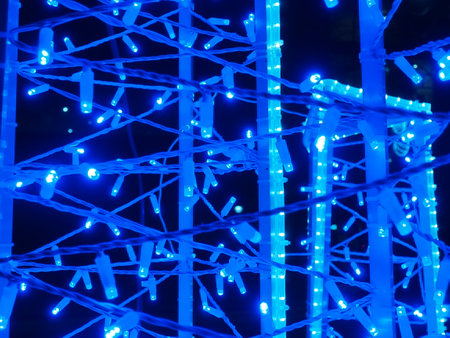 Bokeh from blue garlands. Beautiful festive lighting outdoors. LED bulbs create a New Year and Christmas atmosphere. Background for postcard Happy New Year or Merry Christmasの写真素材