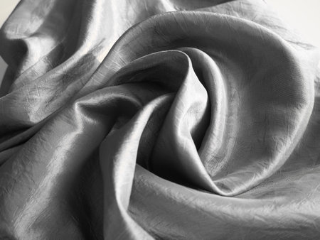 Beautiful fabric - taffeta, gently folded in waves. Crumpled material that looks like silk or brocade. Overflow and color gradient at different lighting angles. Fabric for sewing clothes and curtains.の写真素材