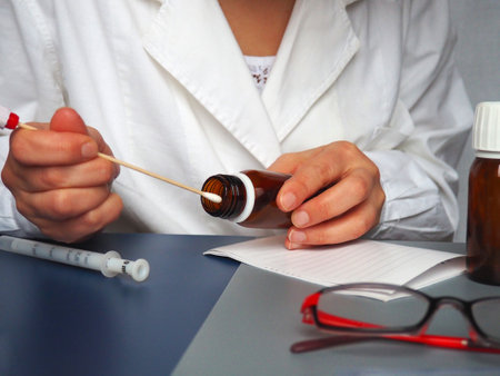 Virus test in the hands of a doctor. Doctor, nurse or laboratory assistant at work in the laboratory. On the table are glasses, measuring instruments, paper, medicines in bottlesの写真素材