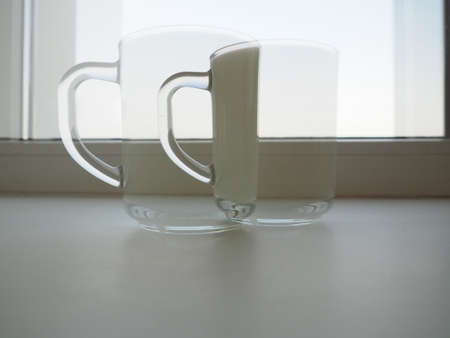 Glass cup with milk on a white background. In the background there is a window frame. Diet protein food. Double exposure or collage.の写真素材