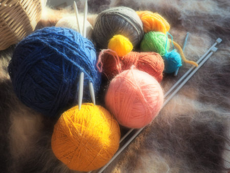 Knitting a scarf or sweater from gray, blue, white and orange yarns. Hanks of woolen and acrylic...