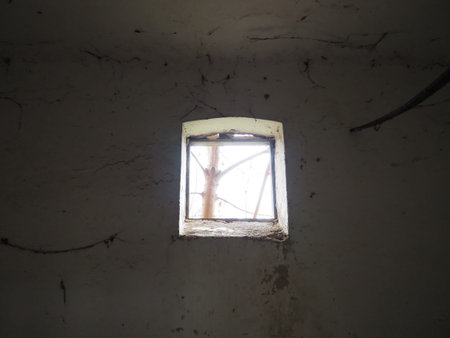 A small window at the top of the wall through which light appears. Scary walls with cobwebs. Old...