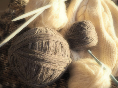 Balls of yarn, knitted clothes, knitting needles and crochet hooks. Knitting as a hobby. Brown,...