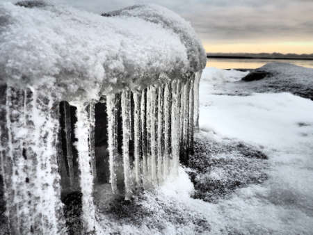 Ice icicles hanging down. Northern arctic winter season. Frozen nature. Retro or vintage style. Black and white image. Frozen water on the lake. Karelia, Russia, December 2020. Lake Onegaの写真素材