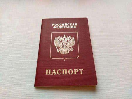 Passport of a citizen of the Russian Federation. International passport for travel and border crossing. Burgundy document cover with embossed gold letters. White background from textile.のeditorial素材