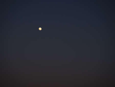 Moon in the night dark blue sky. White point in the sky. Dark vignetting around the edges of the imageの写真素材