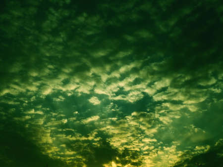 Wonderful sunset. Clouds in the evening sky. The sun's rays pierce the clouds. Green - yellow colors of the sky and clouds. Beautiful landscape. The sun goes down.の写真素材