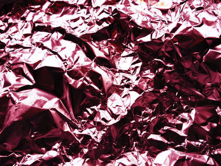 foil close-up. Aluminum silver crumpled foil. Abstract metallic background. Foil for baking food. Background with a red or burgundy tint.の写真素材