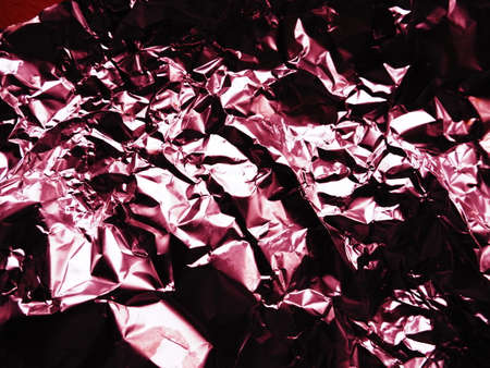 foil close-up. Aluminum silver crumpled foil. Abstract metallic background. Foil for baking food. Background with a red or burgundy tint.の写真素材