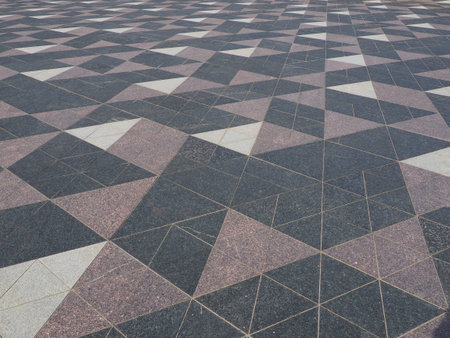 The square is paved with triangular tiles. Gray, white, black tiles on the street. The cobblestone...
