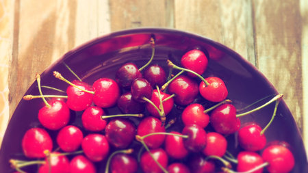 cherry background. Juicy ripe delicious cherry or sweet cherry close-up from above on a dark plate...