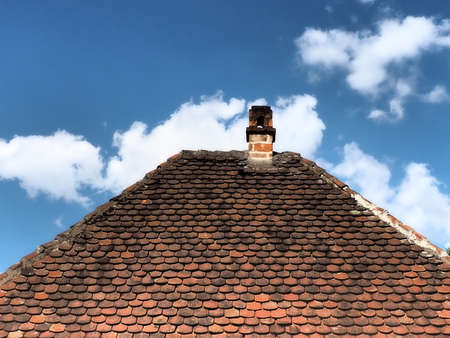 Red roof with a chimney under the blue sky and white clouds. Traditional rustic tiled roof. Serbia, Loznitsaの写真素材