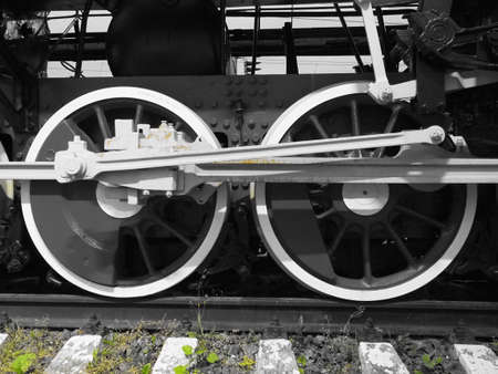 Retro train two wheels. Sleepers and rails, mechanisms, pistons and guides. Locomotive of the 19th early 20th century with a steam engine. Black and white wheels with green grass. Vintage styleの写真素材