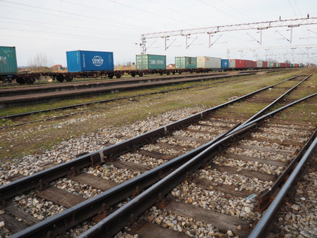Sremska Mitrovica, Serbia, March 28, 2021. Rails and sleepers, railway and stones. Railway traffic, Perspective. Metal rails with concrete sleepers Close-up. Containers in the backgroundのeditorial素材