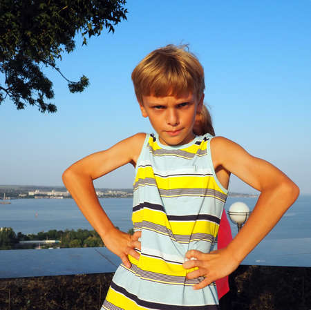 Angry caucasian boy of 8 years old stands in a position of hands on his hips and blocks the body of a girl in a pink dress. Jealousy and competition between children in the family. Aggressive childの写真素材